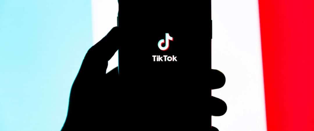 Smartphone mit dem TikTok-Logo vor einem farbigen Hintergrund