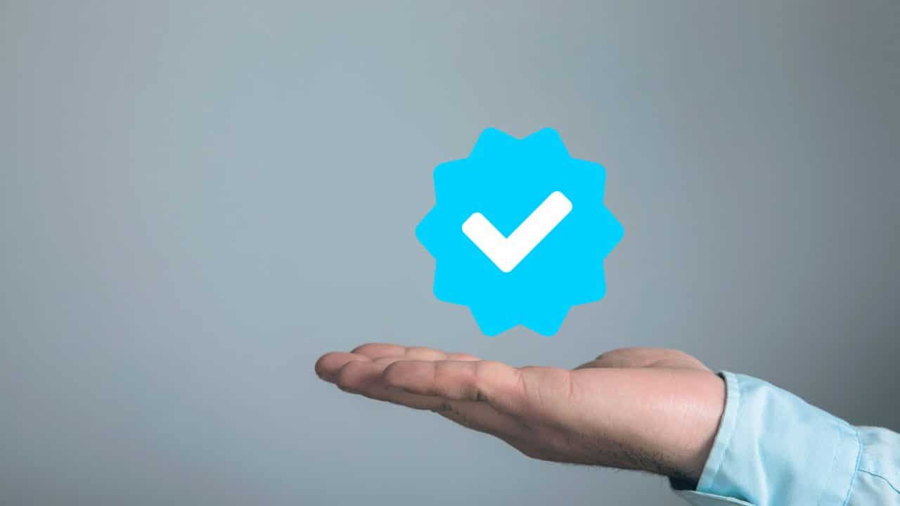 Ein Social Media Verifizierungs-Icon schwebt über einer ausgestreckten Hand.